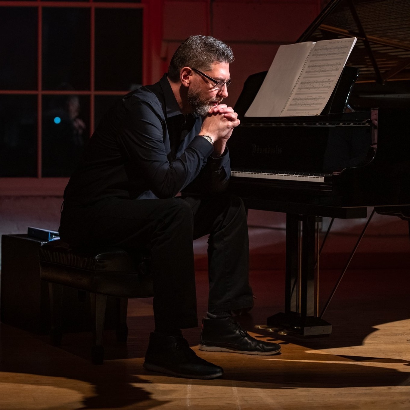 A picture of Chris Foley sitting at a Bosendorfer grand piano.